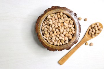 Uncooked dried Chickpeas in a wooden bowl on white background. Preparation for making a hummus dish.High protein ingredient with copy space.  