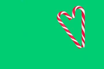 candy cane in the form of a heart on a green background, isolate