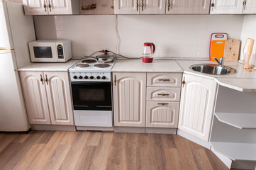 Interior beige small cozy kitchen, cabinets, electric stove