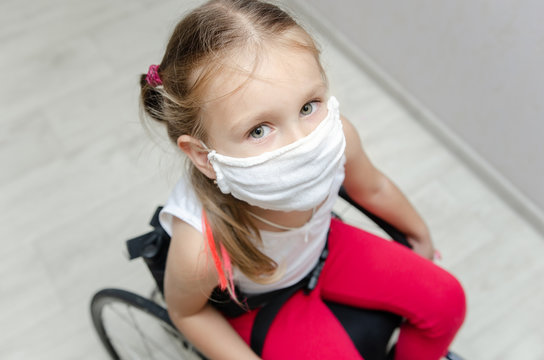 Portrait Of A Disabled Child In A Wheelchair With A Protective Mask On His Face. People With Disabilities During The Coronavirus Pandemic