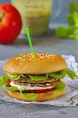 Vegetarian Burger with chickpeas, fresh cucumber, tomato, salad and sour cream sauce. The concept of healthy eating. An alternative to the usual hamburger. Vertical.