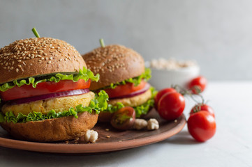 Fresh vegan chickpea burger with onion, tomatoes and lettuce. Home made with vegetables and chickpeas.The concept of healthy and vegetarian food. Place for text. Plant based food concept.