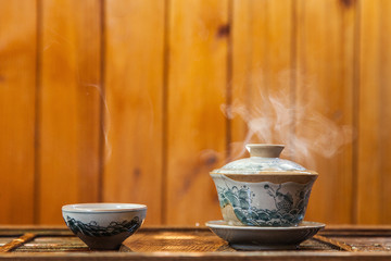 Cup of chinese tea with cloud of steam on wooden background