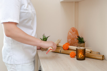 Close-up of the hands of the masseur holding bamboo sticks. Spa, wellness concept on bamboo background	
