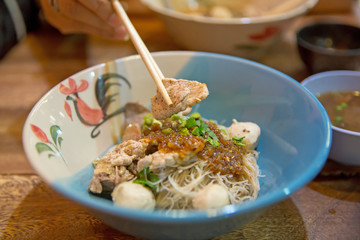 Close up of noodles with pork and pork balls with soup with chopsticks, focus selective.