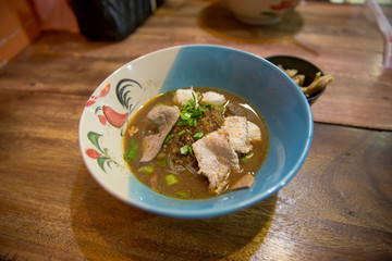 Close up of noodles with pork and pork balls with soup on wood table, focus selective.
