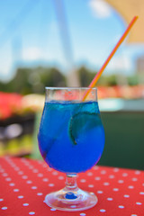 Blue curacao cocktail drink in glass with ice and lemon outside. Cold refreshing summer beverage.