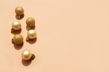 Golden Christmas balls on a delicate beige background and empty space for text