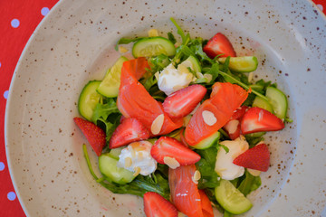 Strawberry and salmon salad with cream cheese served in a plate. Healthy meal. Eating out in restaurant. Summer terrace.