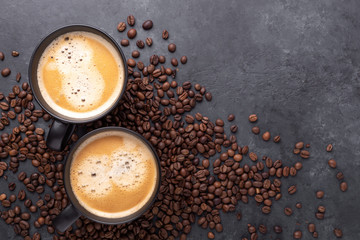 Coffee background. Two black cups with coffee and coffee beans on dark stone background. Copy space for your text. Top view