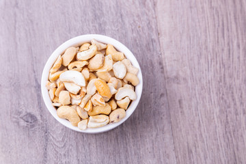 Top view tasty cashew nuts in white bowl on wooden table, Space for text