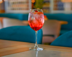 A glass with the red citrus cocktail. Alcohol summer beverage in a wine glass. Refreshing drink with ice.