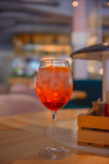 A glass with the red citrus cocktail. Alcohol summer beverage in a wine glass. Refreshing drink with ice.