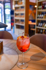 A glass with the red citrus cocktail. Alcohol summer beverage in a wine glass. Refreshing drink with ice.
