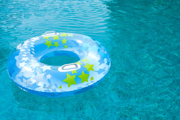 Fototapeta na wymiar Ring floating in a refreshing blue swimming pool. Kids toys. Inflatable rubber circle floating in clear blue water.