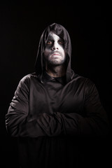 Portrait of grim reaper with hands crossed isolated over black background. Halloween costume.