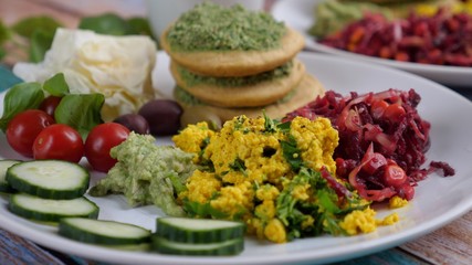 Close up of vegan breakfast of tofu scramble, pancakes and vegetables. Healthy lifestyle concept.