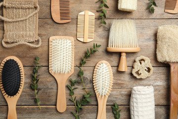 Flat lay composition with hair brushes and combs on wooden background