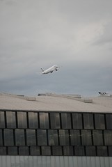 Ein Flugzeug steigt auf, in den bewölkten Himmel.