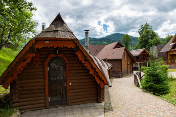 Modern wooden houses from a felling on a background of mountains. Wooden houses with landscaped area on a background of mountains. Traditional wooden cottages at sunny day. 