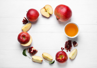Frame of honey, apples and pomegranates on white wooden table, flat lay with space for text. Rosh Hashanah holiday