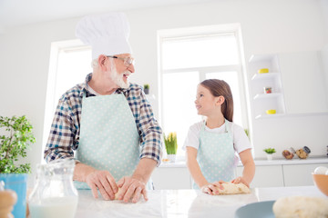 Photo of little girl granddaughter help aged grandpa mixing forming dough baking cookies together best friends leisure activity weekend home kitchen indoors