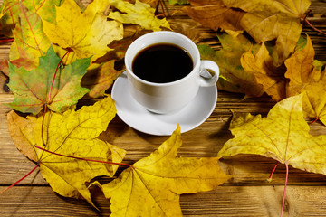 Cup of coffee and autumn maple leaves on wooden table. Autumn concept