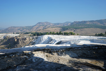 Natural landscape and Thermal pools of Pamukkale (Cotton castle) mineral-rich thermal waters flowing down white travertine terraces on a nearby hillside formed by ancient hot springs- Denizli, Turkey