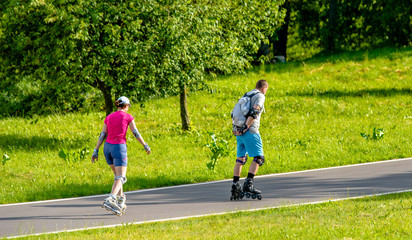 A man and a woman ride on roller skates