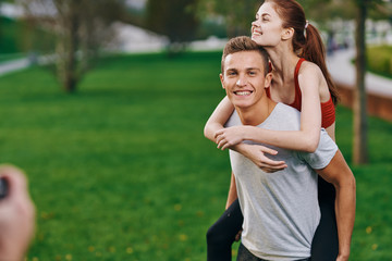 Fototapeta premium happy woman in a red t-shirt on the shoulders of a man in a summer park in nature