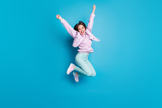 Full length photo of crazy pretty lady jump up supporting sports team cheerleader captain wear casual denim violet jacket sweater pants shoes isolated blue color background