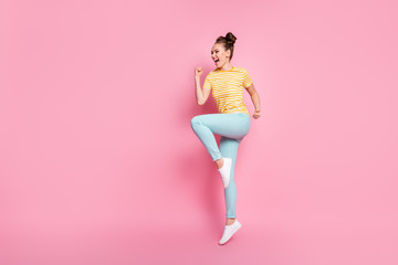 Fototapeta na wymiar Full body profile photo of attractive lady two buns jump high up excited good mood supporting sports team wear casual striped t-shirt pants shoes isolated pink color background