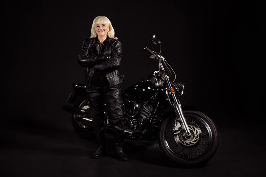 Portrait of her she nice attractive lovely content cheerful cheery grey-haired lady revel rocker chopper lover enjoying club life leisure hobby folded arms isolated over black color background