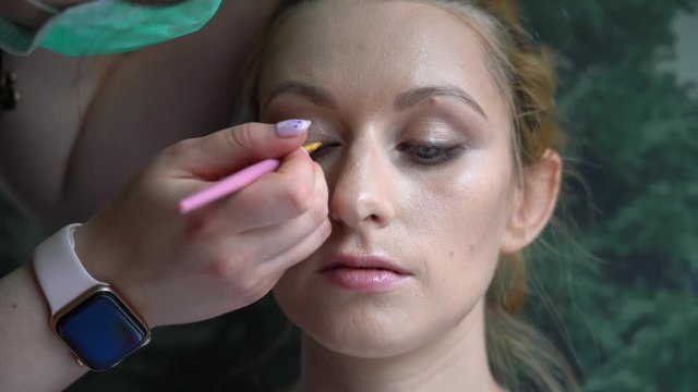 Process of making makeup. Make-up artist applied with brush on model face. Video young ginger woman in beauty salon. Hand of make-up master with brush make perfect skin and color eyeshadow. 4k 