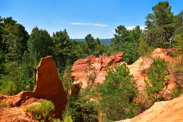 Park Le Sentier des Ocres near Roussillon, France. Orange hills, green trees, blue sky