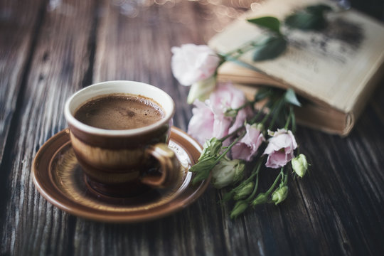 Cup of coffee, book and flowers on a wooden table. Background. Vintage. Postcard.