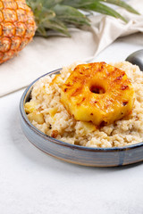 Sweet rice with grilled pineapples and raisins on gray plate on concrete background. Vegetarian food concept .