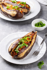 Whole eggplant stuffed with vegetables on white plate on grey background . Imam bayildi, Turkish cuisine.