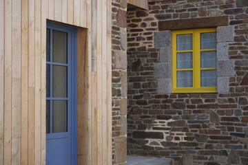 old wooden blue door with yellow windows on an old stone wall