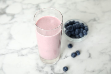 Fototapeta na wymiar Tasty milk shake and blueberries on white marble table