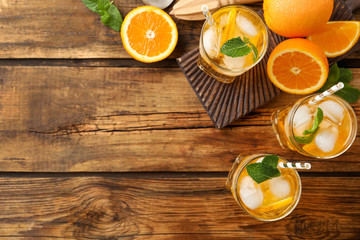 Obraz na płótnie Canvas Delicious refreshing drink with orange slices on wooden table, flat lay. Space for text