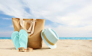 Different stylish beach objects on sand near sea