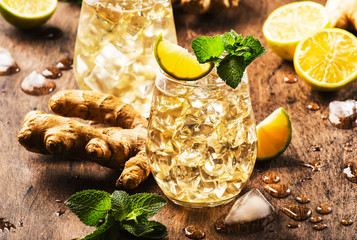 Golden Ginger Ale Beer Cocktail with Lime, Lemon and Mint in glaass on wooden table, copy space