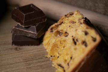 Panettone, typical Italian Christmas cake with chocolate and almonds. In the background the ingredients used to make panettone, eggs, flour, chocolate.
