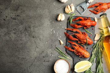 Flat lay composition with delicious red boiled crayfishes on black table. Space for text