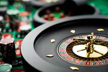 Casino theme, close up of roulette, red and black numbers. Stack of chips in the background.