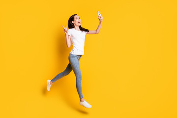 Full length body size view of her she pretty cheerful cheery thin girl jumping strolling taking selfie showing v-sign having fun isolated bright vivid shine vibrant yellow color background