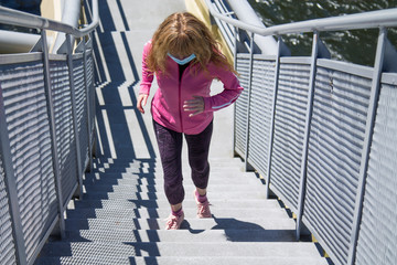 woman with medical mask running through the city, sport concept in the new normal