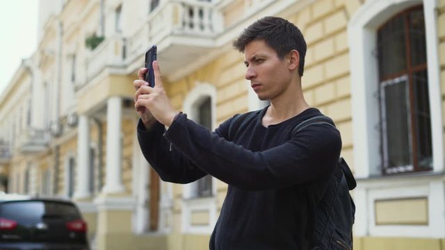 young guy tourist takes photos of architecture for his blog on a smartphone. High quality 4k footage
