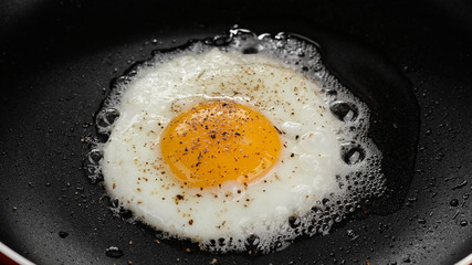 frying egg with seasoning in pan top view